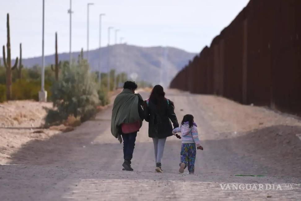 $!Una familia que camina a lo largo del muro fronterizo estadounidense en busca de la Patrulla Fronteriza para ser procesados en Lukeville, Arizona.