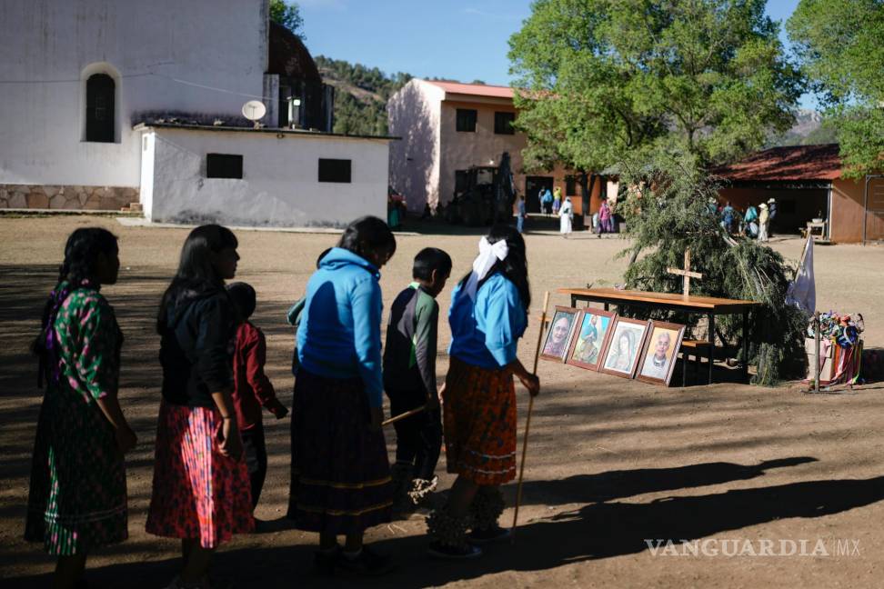 $!Jóvenes indígenas rarámuri caminan hacia un altar donde hay colocados retratos de dos curas jesuitas muertos en Cuiteco, México.