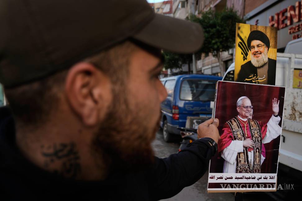 $!Un simpatizante de Hezbolá sostiene fotografías del exlíder del grupo, Hassan Nasrallah y del Papa León XIV en Beirut, Líbano.