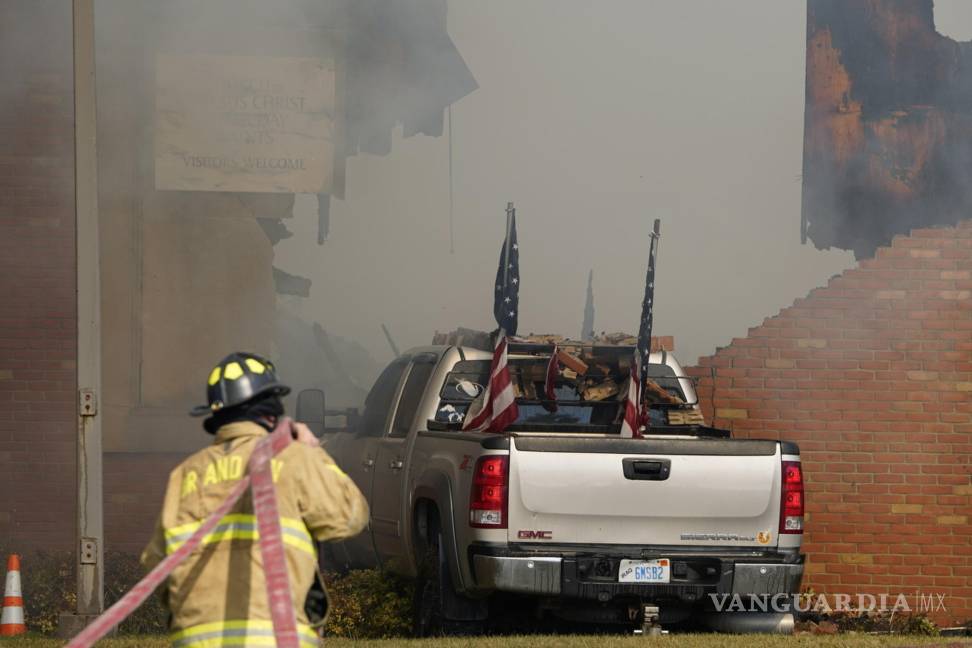 $!Un vehículo embestido contra el edificio está rodeado de humo mientras un bombero trabaja en la Iglesia de Jesucristo de los Santos de los Últimos Días.