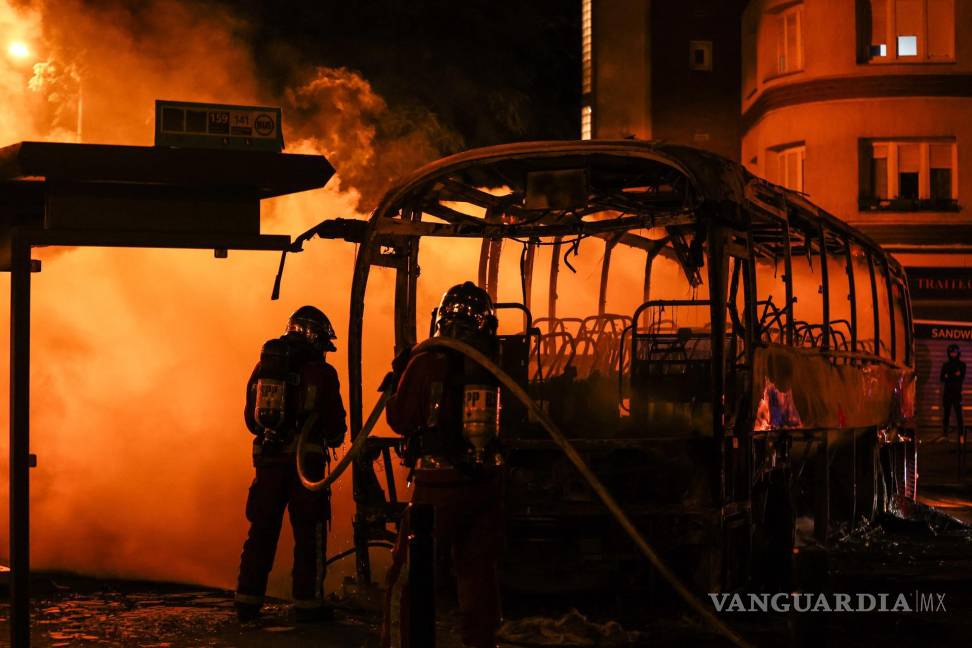 $!Los bomberos extinguen un autobús quemado durante los enfrentamientos entre los manifestantes y la policía antidisturbios en Nanterre, cerca de París, Francia.