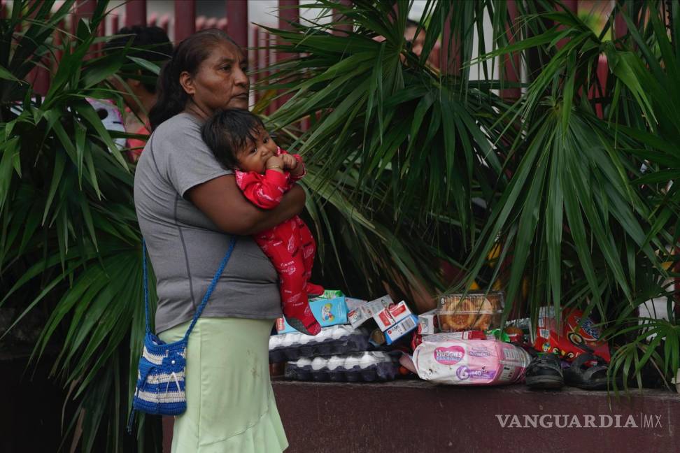 $!Una mujer sostiene a un bebé en brazos junto a varios alimentos tomados de un establecimiento luego del paso del huracán Otis por Acapulco, Guerrero (México).