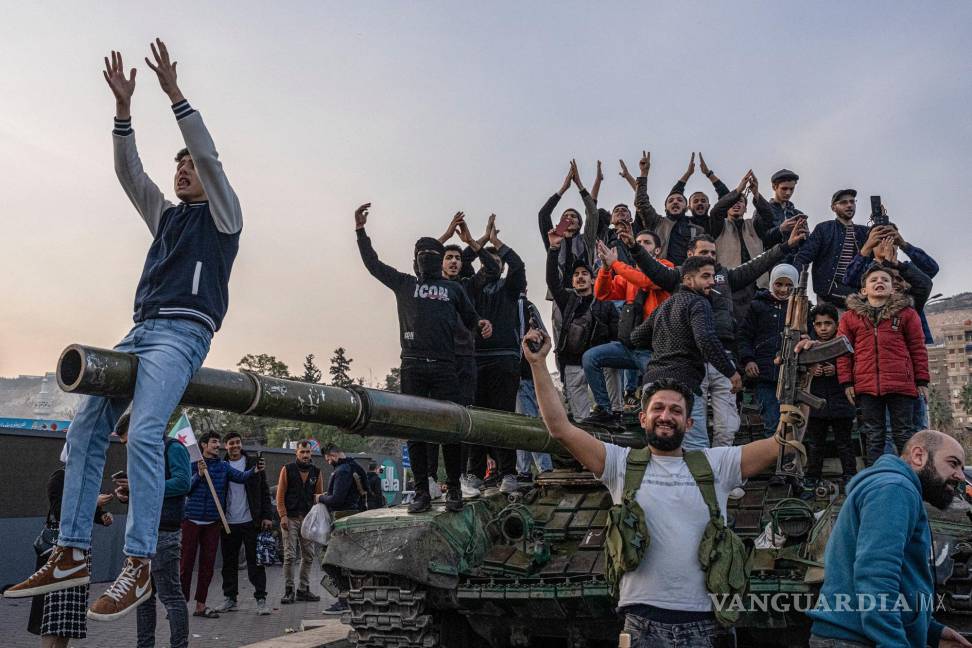 $!Los sirios se reúnen en un tanque en la plaza de los Omeyas en Damasco para celebrar el derrocamiento del presidente Bashar Assad.