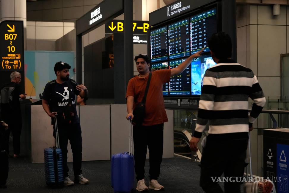 $!Extranjeros observan un panel informativo sobre vuelos en el aeropuerto de Baiyun, en Guangzhou, provincia de Guangdong, al sur de China.