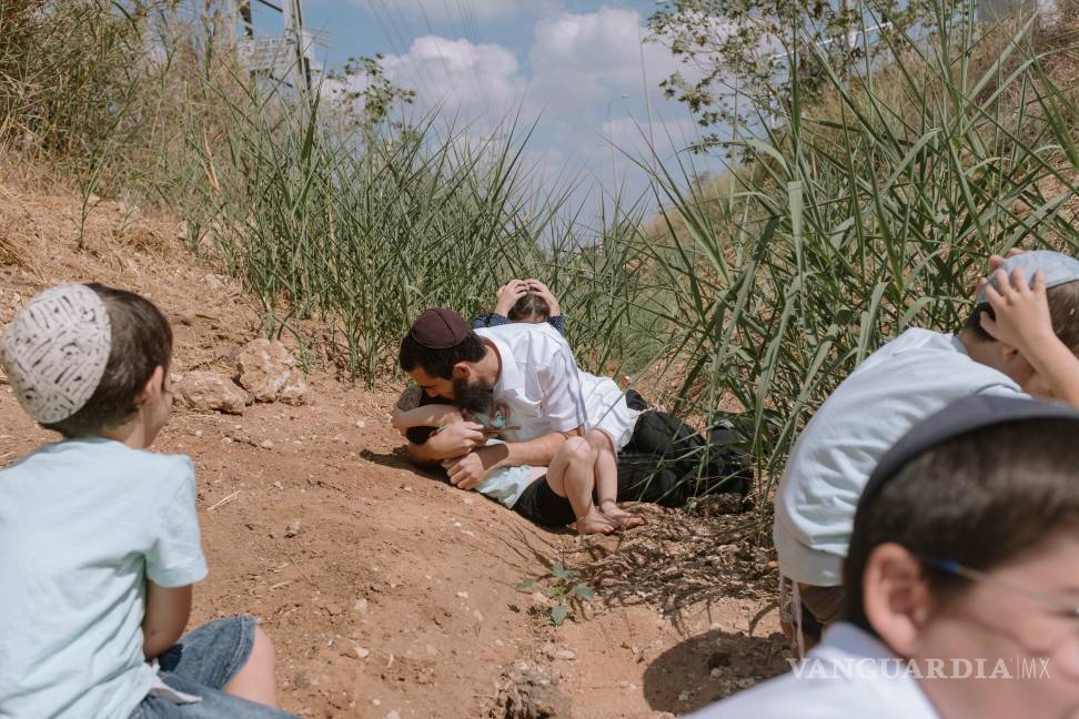 $!Gente se cubre mientras suena una sirena antiaérea para alertar de cohetes lanzados en la Franja de Gaza en Rehovot, Israel, el viernes 13 de octubre de 2023.