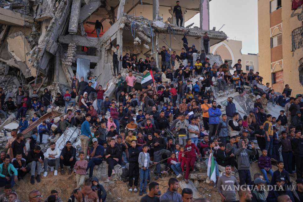$!Palestinos de pie sobre los escombros observan y celebran una boda multitudinaria en Khan Younis, Franja de Gaza.