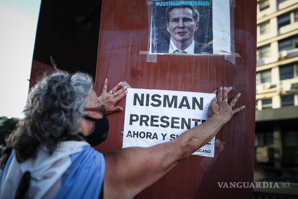 $!Fotografía del 18 de enero de 2021. Una mujer cuelga un cartel en un retrato del fiscal argentino Alberto Nisman, en un acto por el sexto aniversario de su muerte.