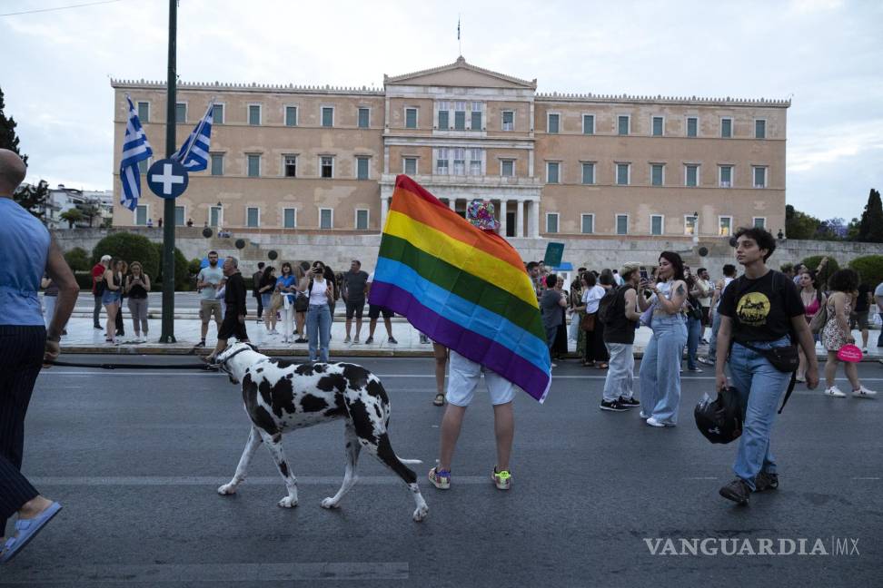 $!Un perro se abre paso mientras un participante iza una bandera del arcoíris frente al parlamento durante el desfile anual del Orgullo, en Atenas.