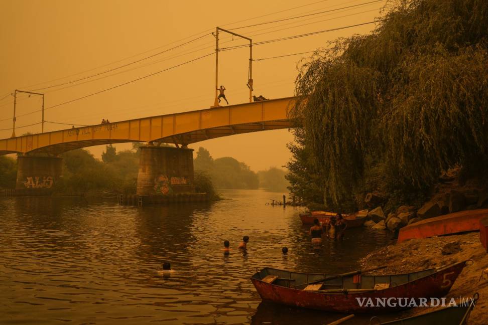 $!Varias personas nadan en el río Renaico bajo un cielo cubierto del humo causado por los incendios, en Renaico, Chile, el 4 de febrero de 2023.
