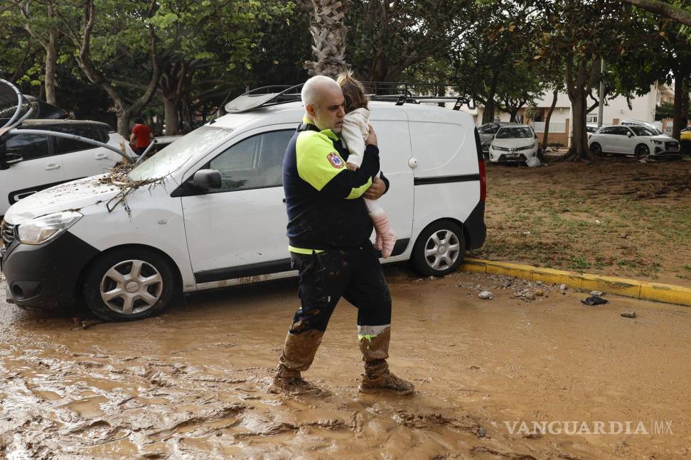 $!Un miembro de transporte sanitario con una niña tras las intensas lluvias de la fuerte DANA en Picaña, Valencia.