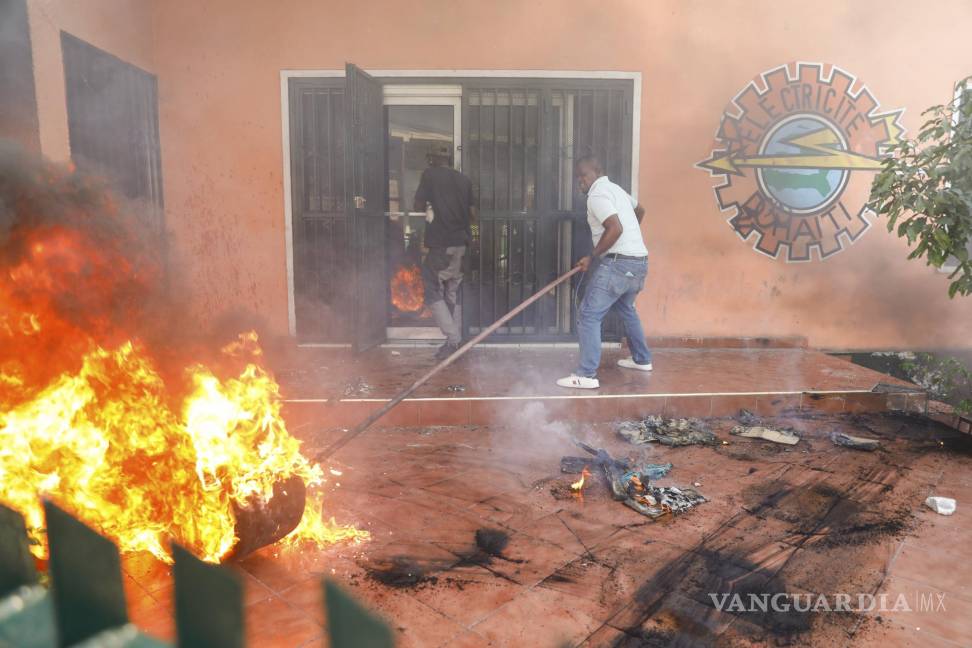 $!Trabajadores apagan un incendio en una oficina de la empresa eléctrica del país durante una protesta para exigir la renuncia del primer ministro, Ariel Henry.