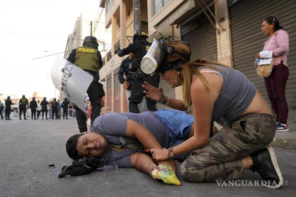 $!Una mujer atiende a un manifestante de oposición que cayó al suelo durante una marcha contra la presidenta peruana Dina Boluarte en Lima, Perú.