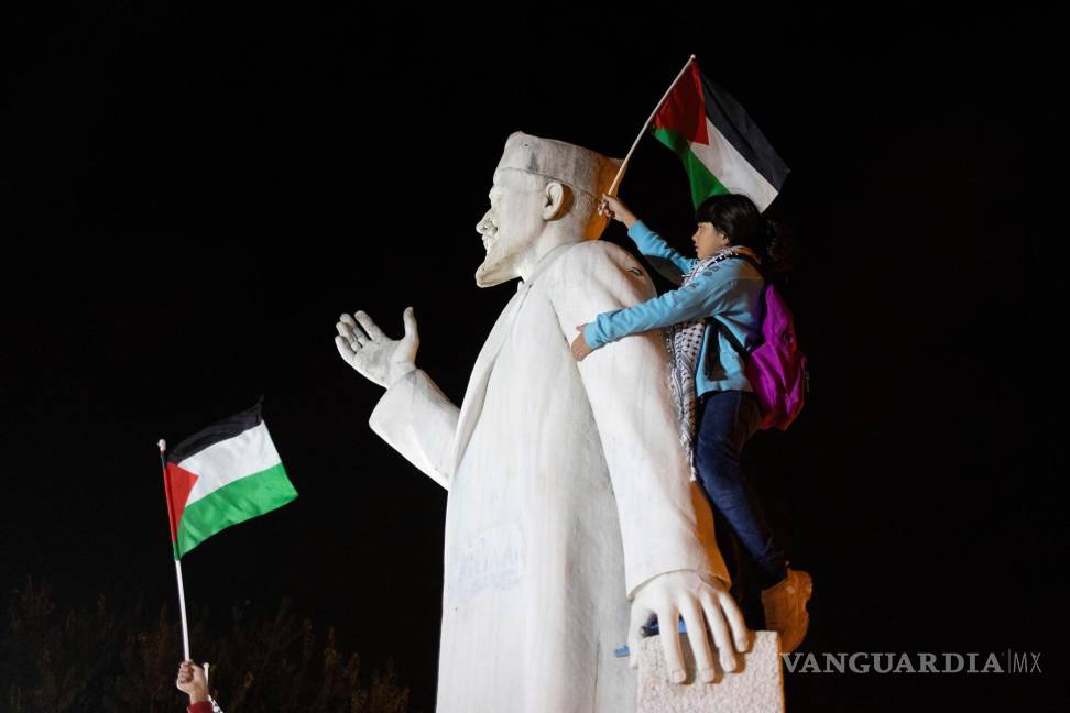 $!Un manifestante sobre una estatua iza la bandera palestina mientras los palestinos que viven en Grecia piden por “Palestina libre” en Salónica, Grecia.