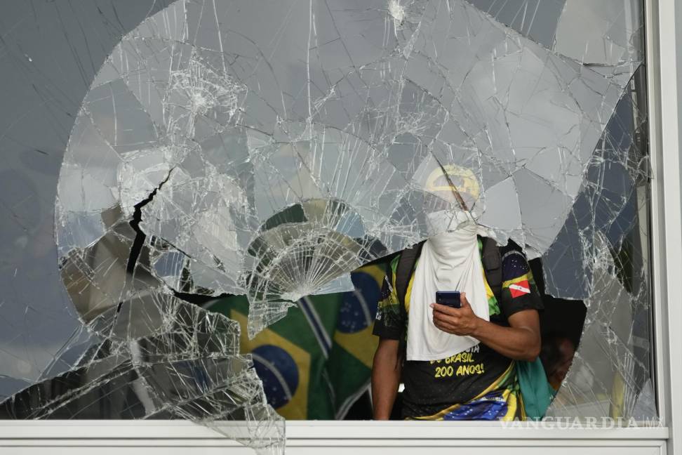 $!Los manifestantes, simpatizantes del expresidente de Brasil, Jair Bolsonaro, hacen pucheros desde una ventana rota después de asaltar el Palacio Planalto en Brasilia.