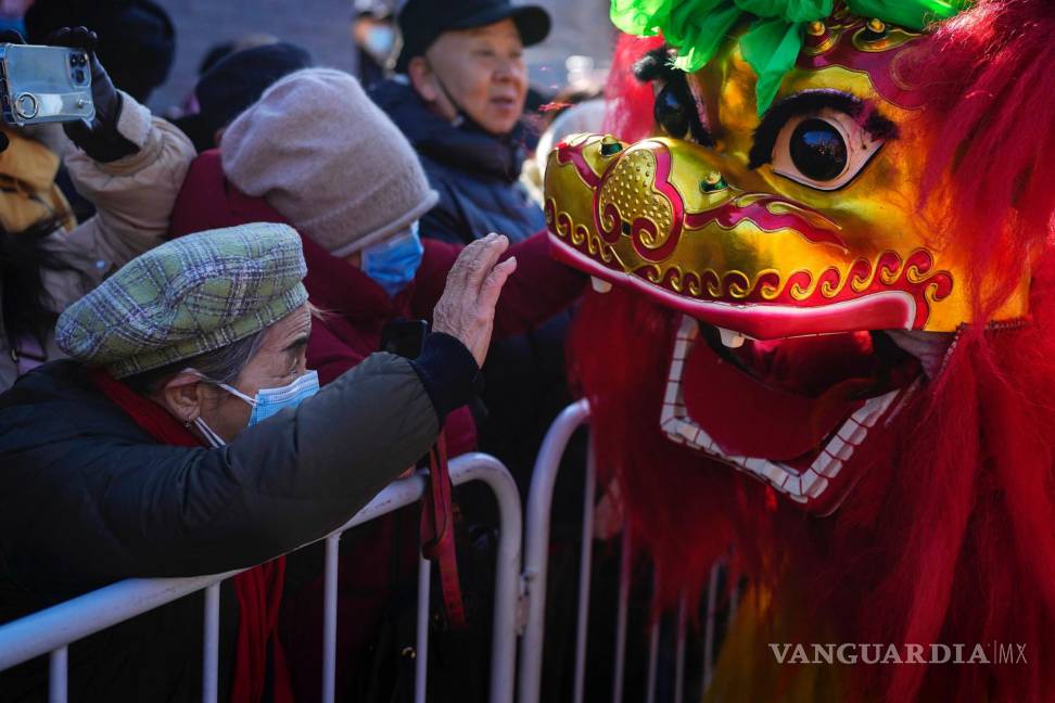 $!Una mujer toca un león danzante mientras los residentes asisten a un festival en el templo de Dongyue, en el primer día del Año Nuevo Lunar, en Beijing.
