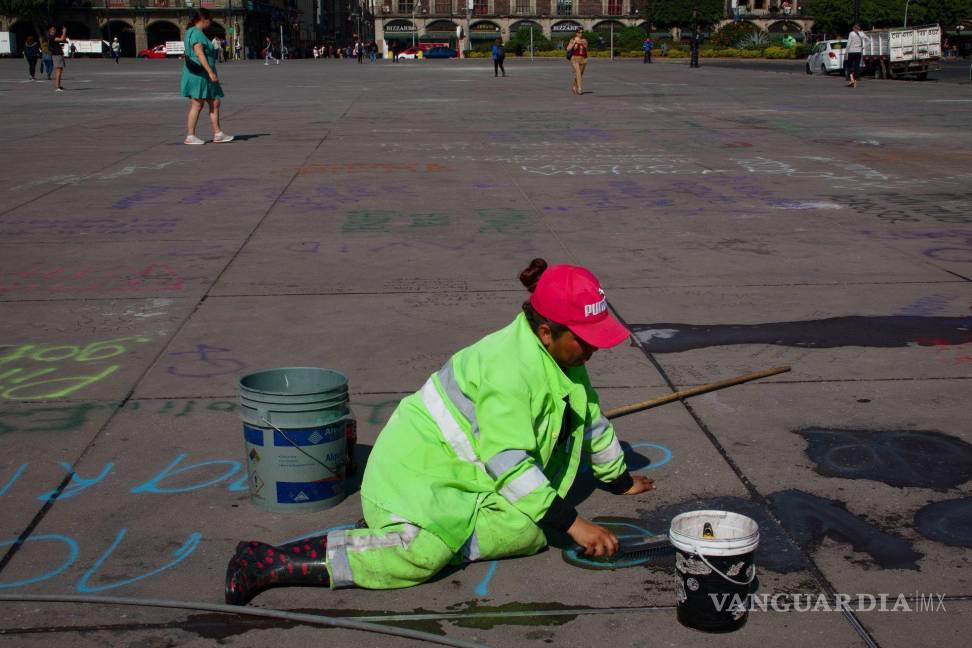 $!Una trabajadora realizan limpieza de pintas en la plancha del Zócalo en CDMX.