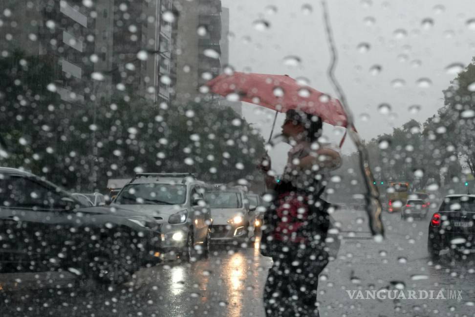 $!Un peatón con un paraguas cruza la calle durante una lluvia en Buenos Aires, Argentina, el 20 de marzo de 2024.