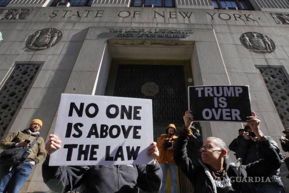 $!Varias personas sostienen carteles que dicen nadie está por encima de la ley y Trump está acabado durante una protesta el lunes 20 de marzo de 2023 frente a la corte donde será encausado el expresidente.
