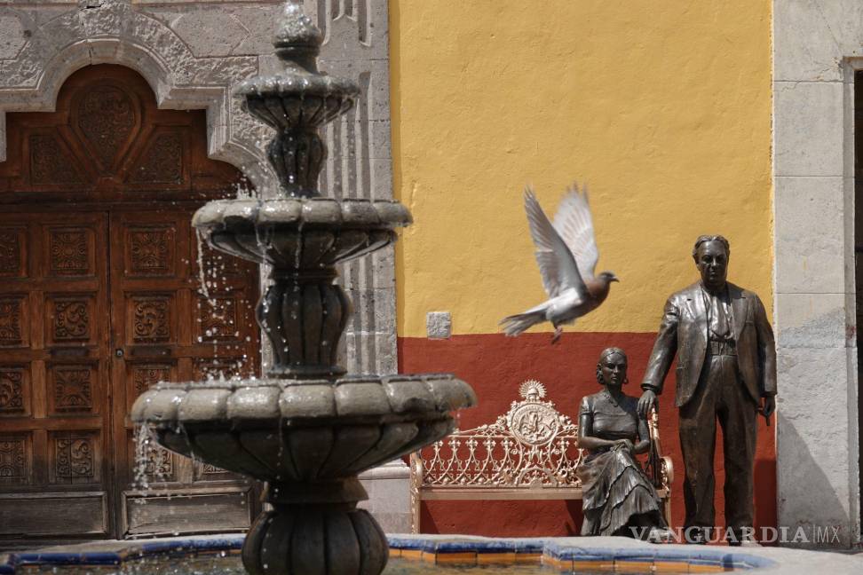 $!Una paloma vuela enfrente de una escultura de los pintores Diego Rivera y Frida Kahlo, en la alcaldía Coyoacán.