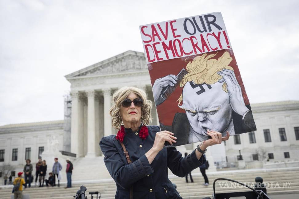 $!Un manifestante sostiene un cartel frente a la Corte Suprema donde los jueces superiores dictaminaron que rump aparezca en la boleta electoral de Colorado.