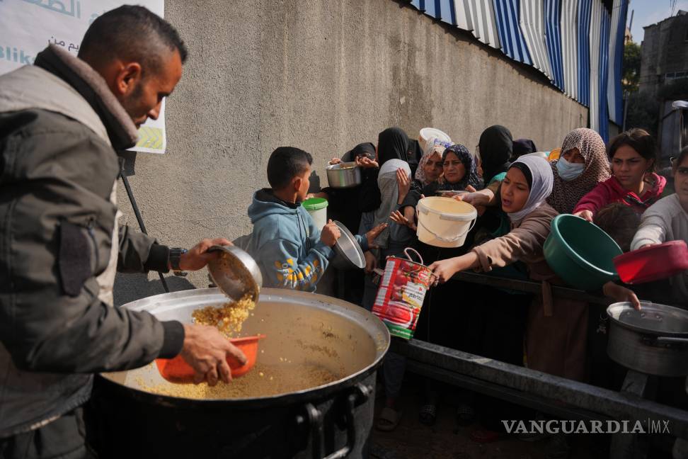 $!Mujeres palestinas luchan por recibir alimentos donados en un comedor comunitario en Nuseirat, en el centro de la Franja de Gaza.
