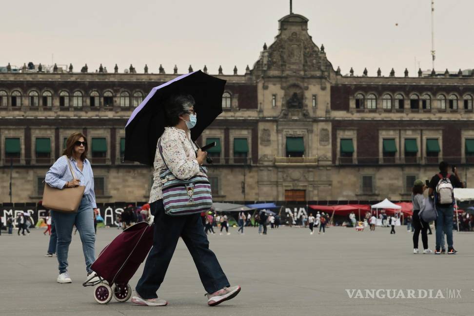 $!Una mujer camina con sombrilla para protegerse del sol en Ciudad de México.