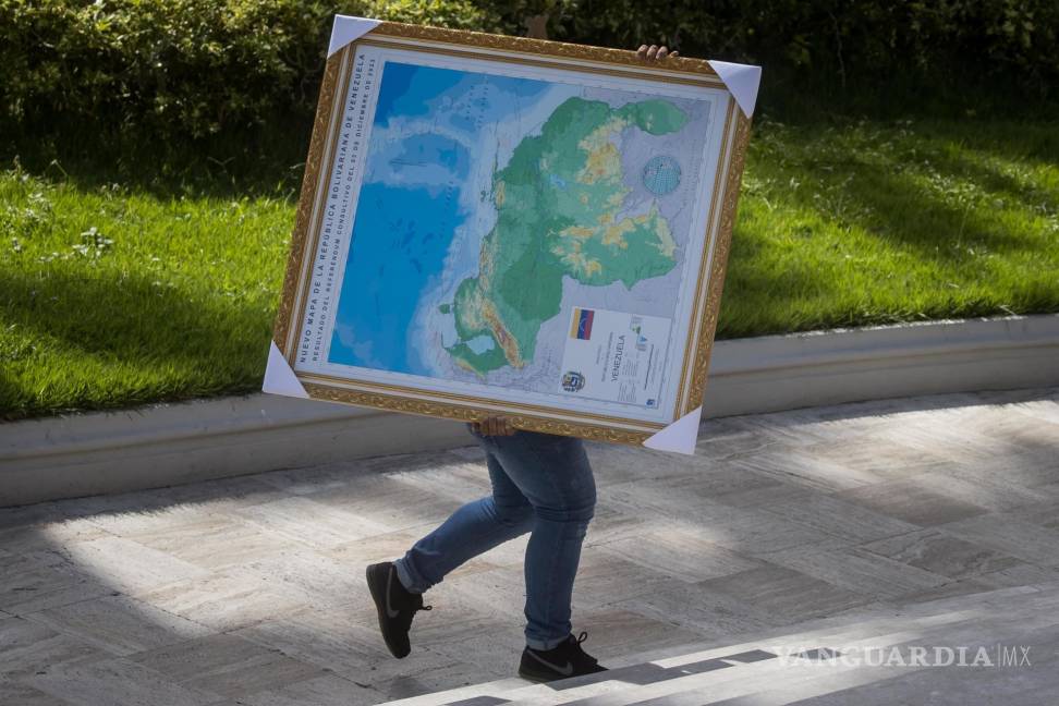 $!Un hombre carga un cuadro del mapa de Venezuela con la adhesión del Esequibo, en uno de los jardines del Palacio Federal Legislativo en Caracas, Venezuela.