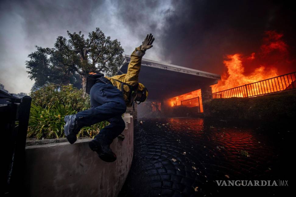 $!Un bombero salta una valla mientras lucha contra el incendio de Palisades en el barrio de Pacific Palisades de Los Ángeles.