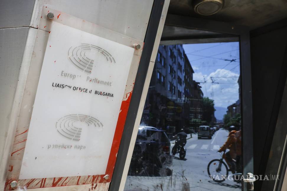 $!El tráfico en la calle se refleja junto a un cartel dañado del Parlamento y la Comisión Europea en Sofía, Bulgaria.