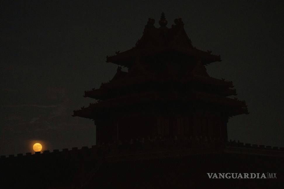 $!La torre de la esquina de la Ciudad Prohibida se recorta cerca del anochecer cuando una superluna se eleva cerca del horizonte en Beijing, China.