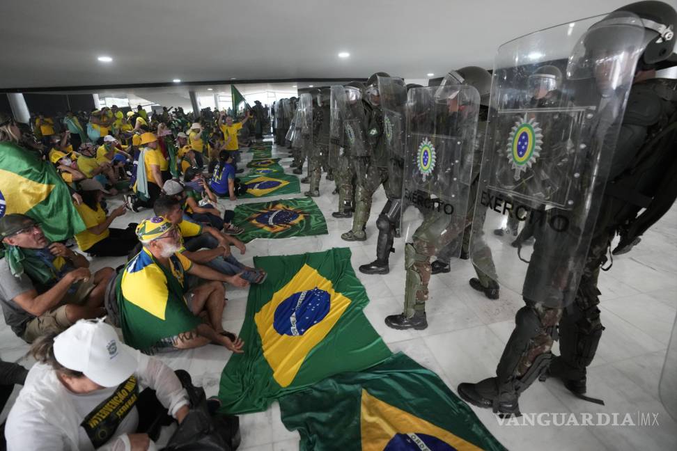 $!Simpatizantes del expresidente de Brasil, Jair Bolsonaro, se sientan frente a la policía después de entrar al Palacio de Planalto después de asaltarlo, en Brasilia.