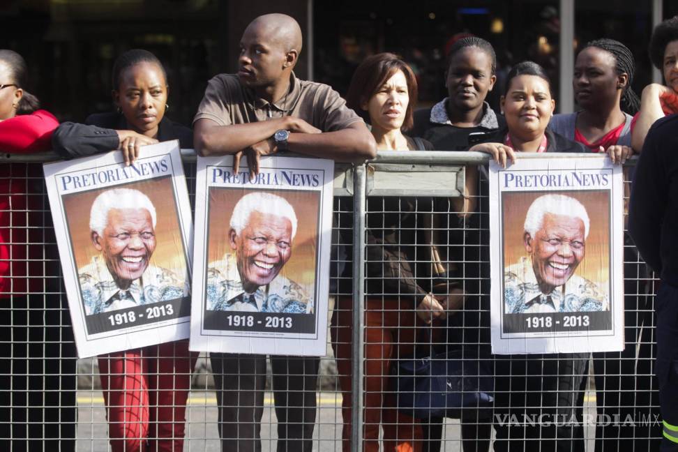 $!Sudafricanos sujetan carteles con la imagen de Madiba mientras aguardan la llegada del cortejo fúnebre con los restos mortales del expresidente sudafricano.