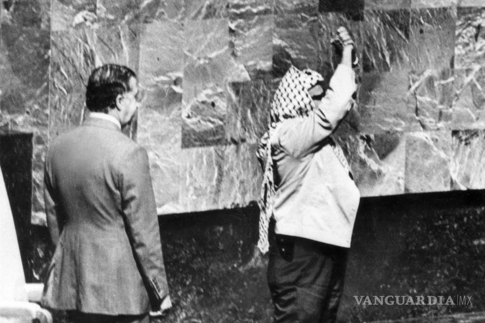 $!Una funda de pistola sobresale debajo de la chaqueta de Yasser Arafat mientras junta las manos sobre su cabeza en su aparición ante la Asamblea General de Naciones Unidas en la sede del organismo, el 13 de noviembre de 1974.