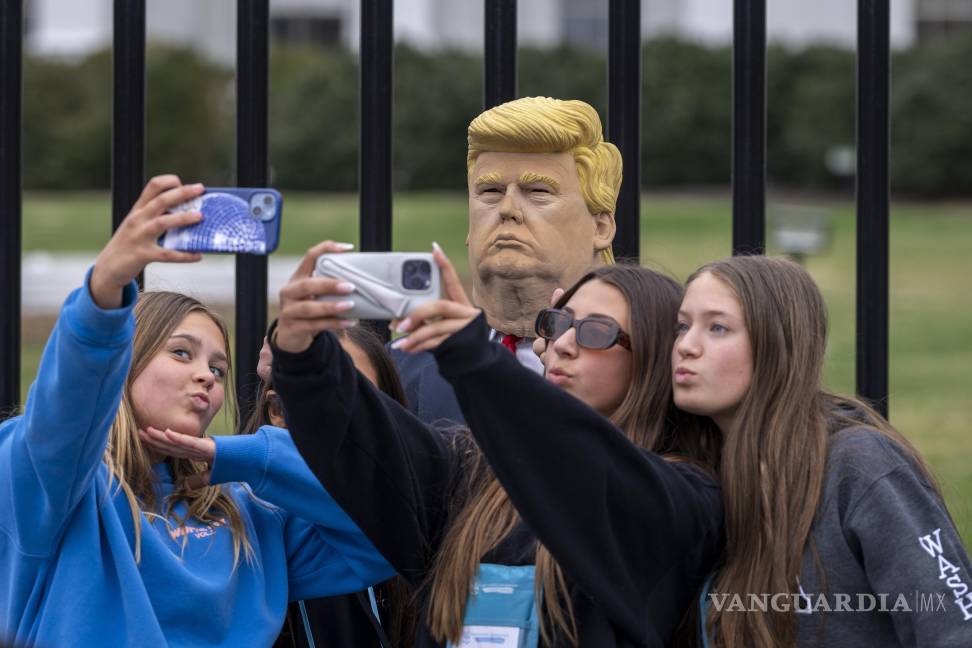 $!Un grupo de jóvenes visitantes posa para una foto con otro visitante de la ciudad que lleva una máscara del presidente Donald Trump frente a la Casa Blanca.