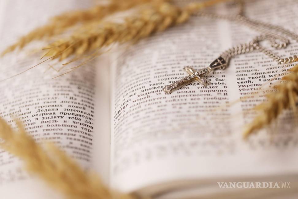 $!Collar de plata con crucifijo sobre página de la Biblia.