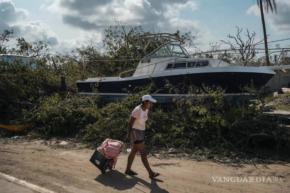 $!Una residente pasa junto a un bote cuando llega a su casa para recuperar artículos personales y alimentos después del huracán Otis en Acapulco, México.