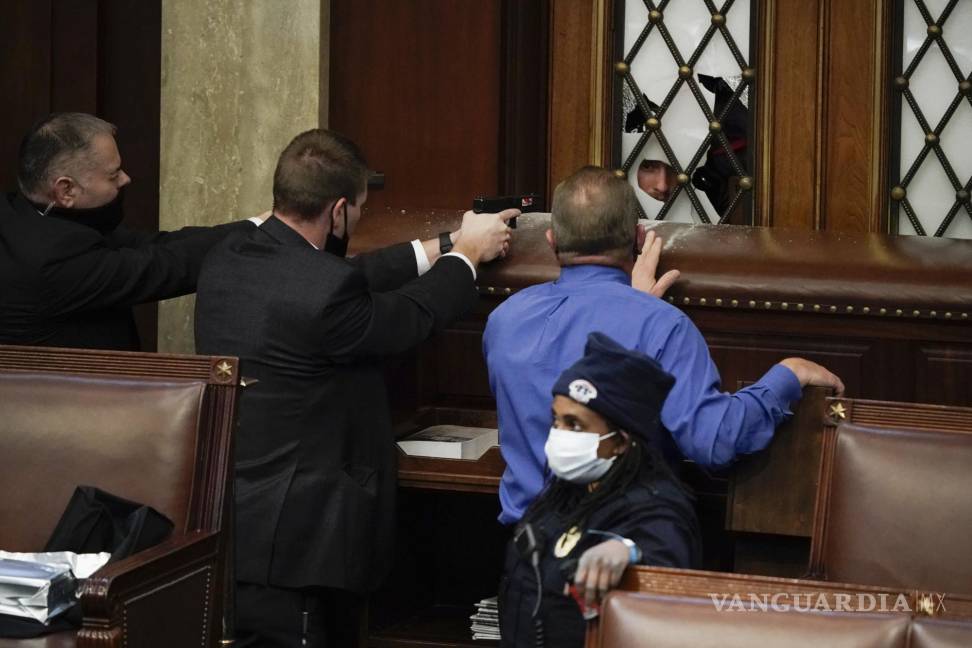 $!La policía del Capitolio observa cómo los alborotadores intentan irrumpir en la Cámara de la Cámara de Representantes en el Capitolio. AP/J. Scott Applewhite