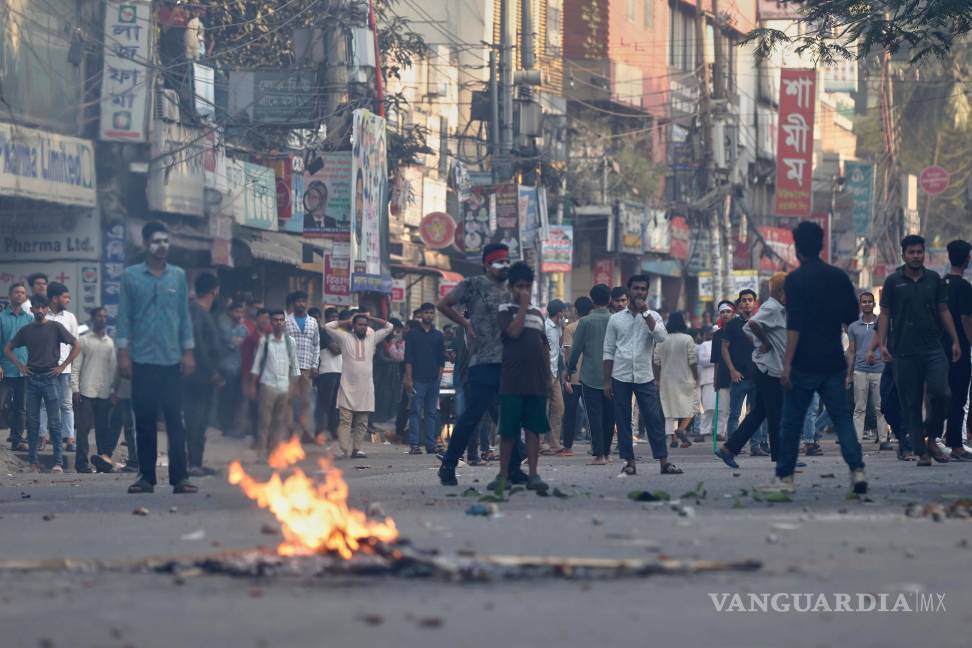 $!Manifestantesse enfrentan con la policía frente a la residencia demolida del padre de la derrocada primera ministra Sheikh Hasina tras el veredicto en su contra.