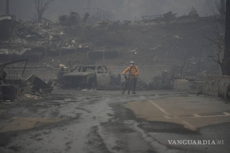 $!Una persona anda en bicicleta por una zona quemada mientras el incendio de Palisades arrasa un vecindario en el vecindario Pacific Palisades de Los Ángeles.