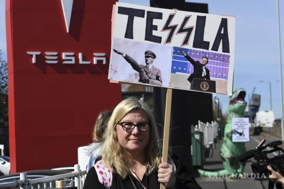 $!Una manifestante sostiene una pancarta mientras participa en el Día de Acción Global para Derribar Tesla cerca de un concesionario de Tesla en Londres.