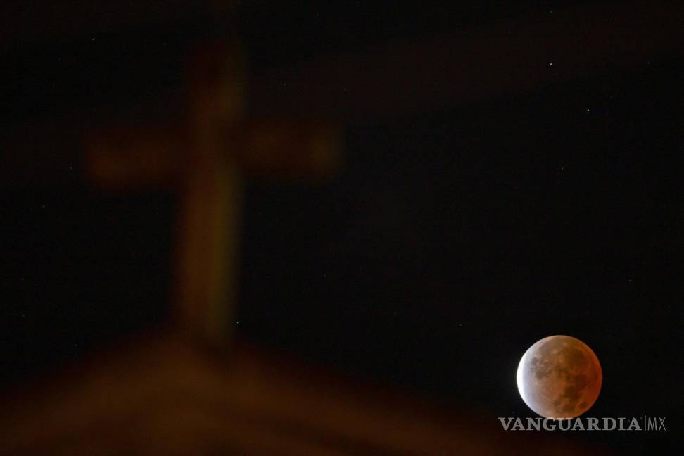 $!Una vista del eclipse lunar detrás de la iglesia de St. Williams en Cincinnati. El eclipse fue el más largo de este siglo y más largo que cualquier otro eclipse que se remonta a 580 años. AP/Albert Cesare /The Cincinnati Enquirer