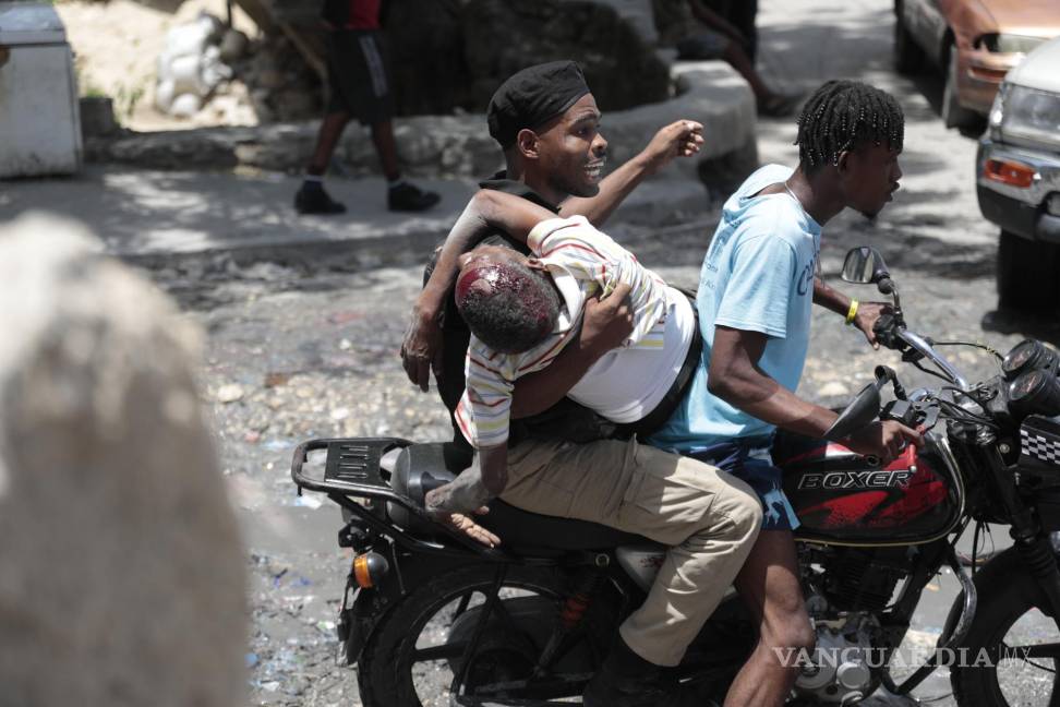 $!Un agente de policía agarra a un hombre herido durante enfrentamientos violentos entre bandas en Puerto Príncipe, Haití, el 15 de agosto de 2023.