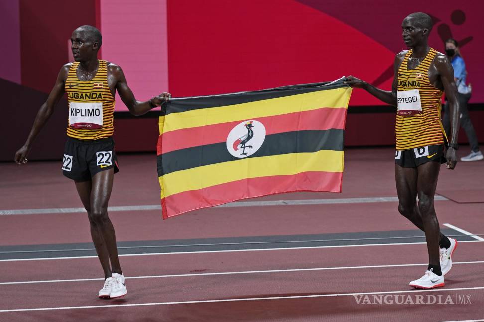 $!El segundo clasificado Joshua Cheptegei, a la izquierda, de Uganda, y su compañero de equipo tercero Jacob Kiplimo celebran con su bandera nacional después de las carreras en la final masculina de 10.000 metros. Foto: (AP Photo/David J. Phillip)