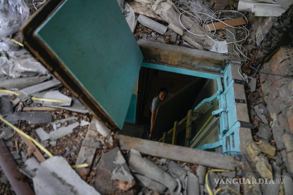 $!Liudmyla Voronina se ve a través de la trampilla de su tejado mientras está de pie en su casa, dañada por los ataques en Irpin, Ucrania, el jueves 26 de mayo de 2022.