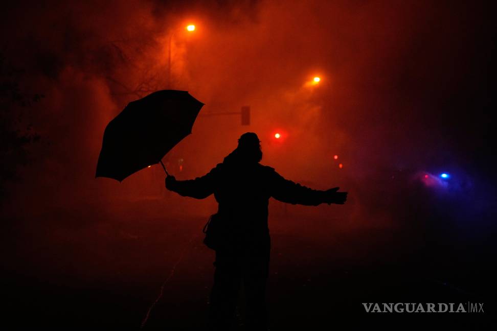 $!Un manifestante sostiene un paraguas mientras reacciona al gas lacrimógeno tras un tiroteo el miércoles 14 de enero de 2026 en Minneapolis.