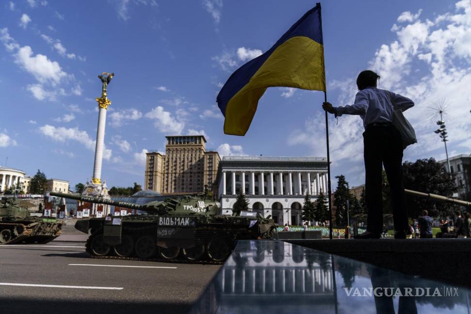 $!Una mujer sostiene la bandera de Ucrania mientras observa una fila de vehículos militares rusos destruidos en exhibición en la plaza Maidan en Kyiv, Ucrania.