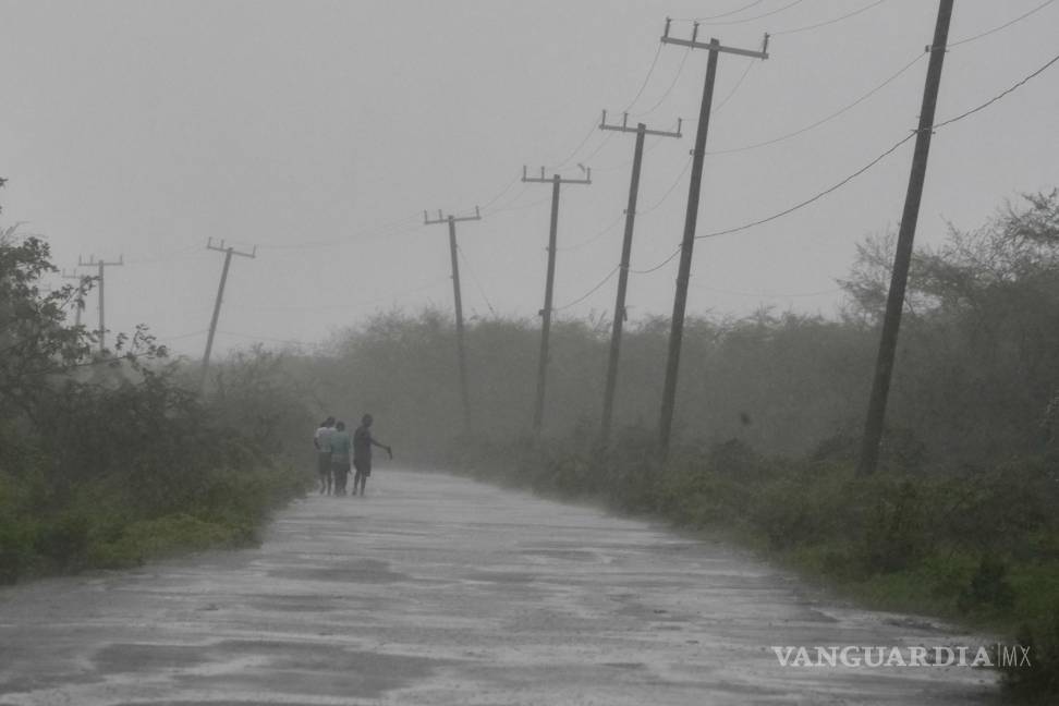 $!Personas caminan por una carretera durante el paso del huracán Melissa en Rocky Point, Jamaica.