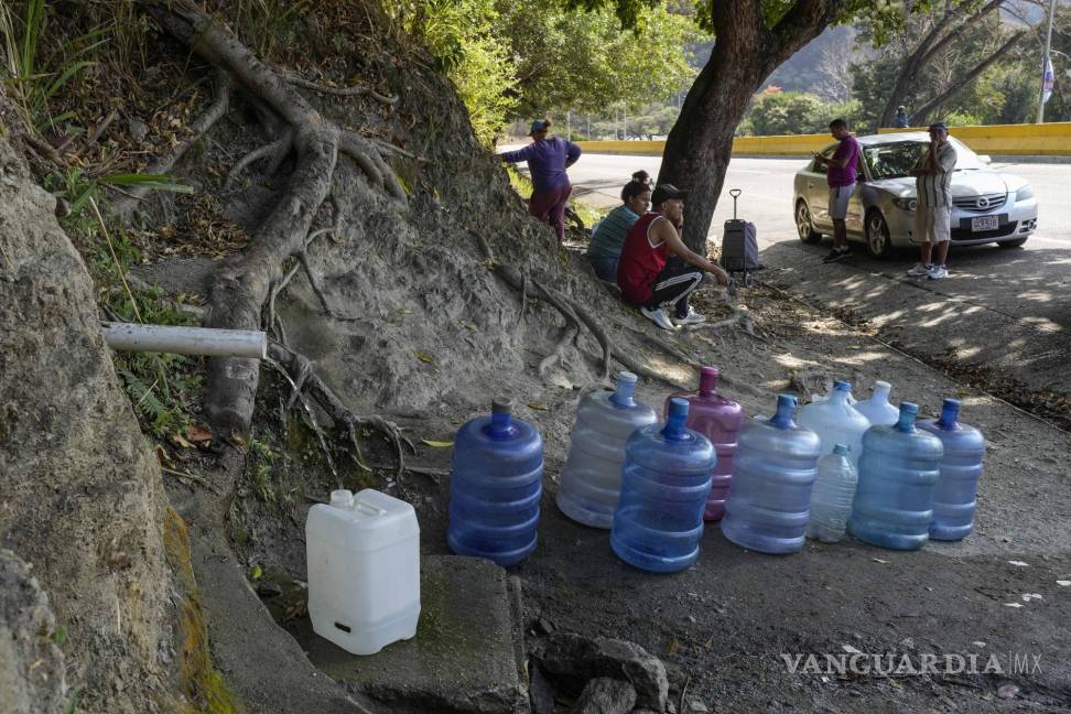 $!La gente recoge agua de una montaña al costado de la carretera para llevarla a casa en Caracas, Venezuela.