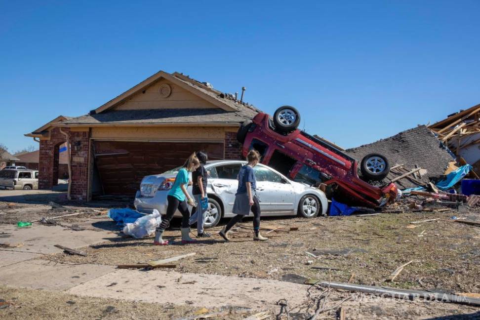 $!Vecinos pasan ante una casa dañada por el tiempo en Wheatland Drive y Conway Drive en Norman, Oklahoma.