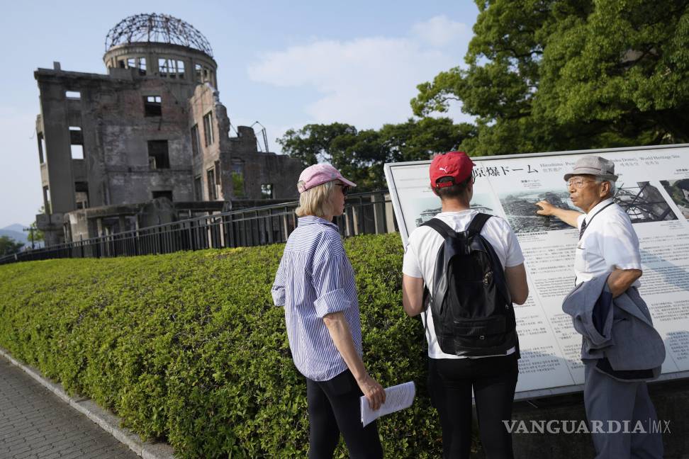 $!Kunihio Iida, sobreviviente de la bomba atómica y guía voluntario habla en inglés a visitantes extranjeros frente a la Cúpula de la Bomba Atómica en Hiroshima.